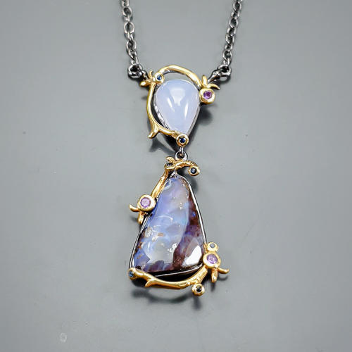 Κολιέ σε ασήμι 925 με μαύρο και κίτρινο επιχρύσωμα στα 14Κ με φυσικό Αυστραλιανό Οπάλιο σε κοπή Fancy με Opaque διαφάνεια καθαρότητα υπέροχα χρώματα και βάρος 25.88 ct, ένας Χαλκηδόνιος σε Μοβ/γκρι χρώμα σε κοπή pear cab  με ημιδιαφανεια στα 5.50 ct. Το κόσμημα συμπληρώνουν 3 Αμέθυστοι  σε Round κοπή με Vvs διαφάνεια καθαρότητα και βάρος 0.45 ct  και 7 μαύροι Σπινέλιοι σε στρογγυλή κοπή και βάρος 0.14 ct. Η προέλευση των λίθων είναι απο την Αυστραλία και την Αφρική.