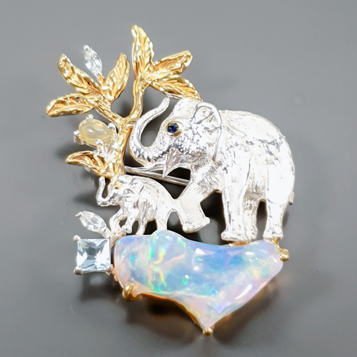 Καρφίτσα σε ασήμι 925 με λευκό και κίτρινο επιχρύσωμα στα 18Κ με ένα Raibow Οπάλιο σε κοπές Free Form & Oval Cab με If-Vvs διαφάνεια καθαρότητα στα 10.83 ct με υπέροχους ιριδισμούς και πανέμορφα χρώμα να βγαίνουν απο το εσωτερικό των λίθων. Το κόσμημα συμπληρώνουν και δύο Ακουαμαρίν σε κοπές princess & Marquise με If διαφάνεια καθαρότητα και έντονο γαλάζιο χρώμα. Η προέλευση των λίθων είναι από την Αιθιοπία και την Βραζιλία.